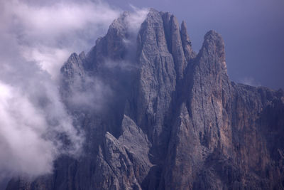 Low angle view of rocky mountains against sky with clouds