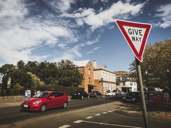 Road sign by street against sky in city