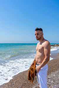 Man standing at beach against clear sky