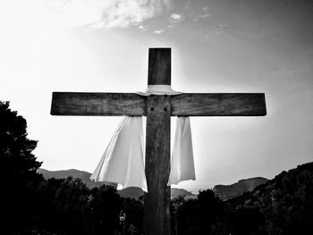 Low angle view of cross by building against sky