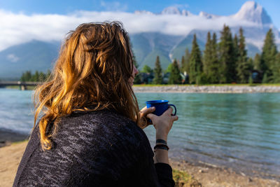 Rear view of woman looking at lake against mountain