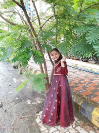 Portrait of girl standing against trees