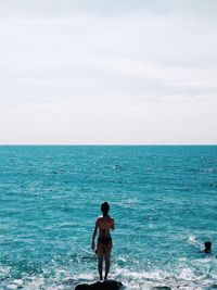 Rear view of man standing in sea against sky