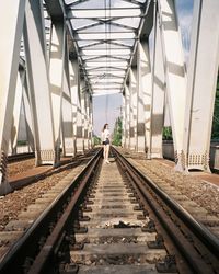 Rear view of woman looking over shoulder standing on railroad tracks