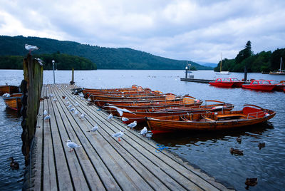 Boats moored on pier by sea against sky