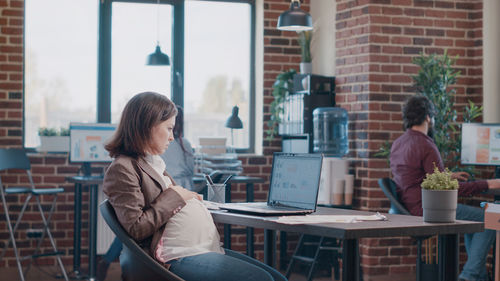 Pregnant businesswoman working on laptop at office