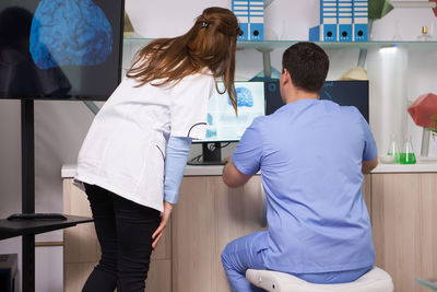 Rear view of female doctor examining patient at clinic