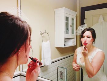 View of bride applying lipstick in bathroom