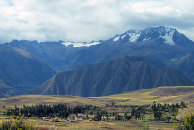 Scenic view of landscape and mountains against cloudy sky