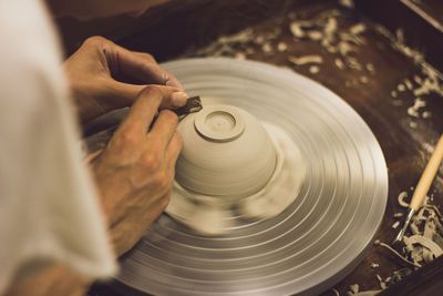 Cropped hands of person working on pottery wheel