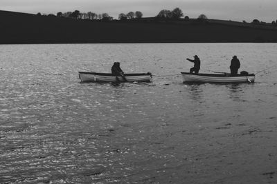 People on boat in lake against sky