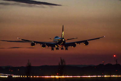 Airplane flying in sky at sunset