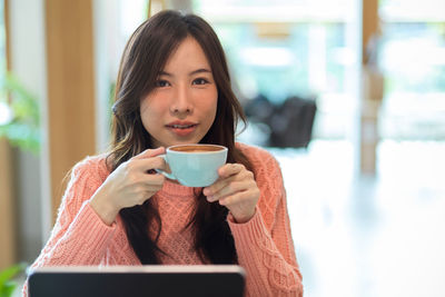 Portrait of woman drinking coffee at cafe