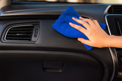 Cropped hand of woman cleaning dashboard of car