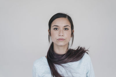 Portrait of a young woman wearing her ponytail wrapped around her neck