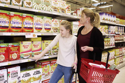 Mother and daughter choosing corn flakes in supermarket