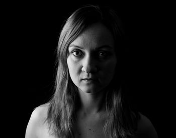 Close-up portrait of a beautiful young woman over black background