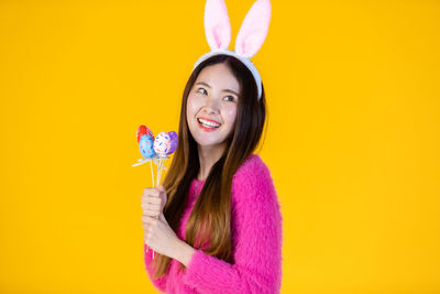 Portrait of a smiling young woman against yellow background