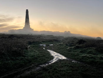 Carn brea monument, almost submerged in light fog, moment before sunset