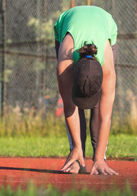 Female runner practise yoga and stretching body from back to legs cramp at the stadium