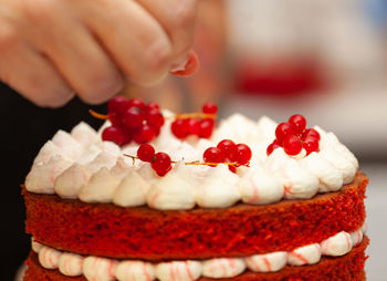 Baker cooking red velvet cake, putting currant berries.