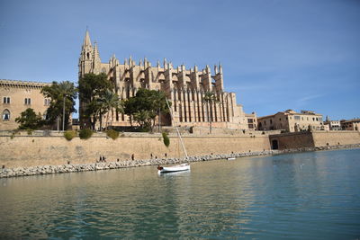 View of buildings by river against sky in city