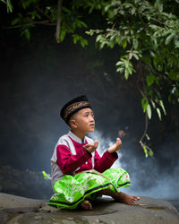 Girl looking away while sitting on plant