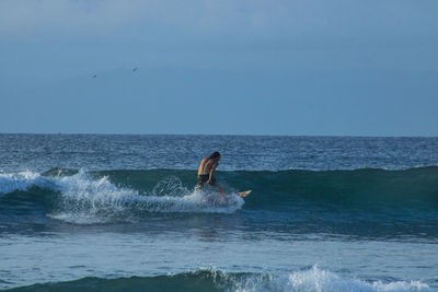 Man surfing in sea against sky