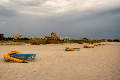 Deck chairs on beach by sea against sky