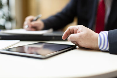 Midsection of man using smart phone on table