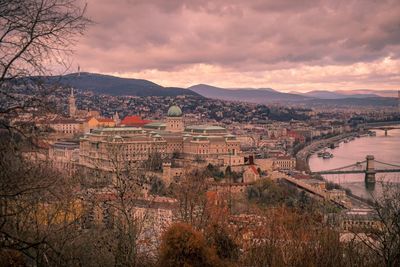 High angle view of buildings and river against sky at sunset