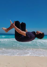 Man surfing in sea against clear blue sky