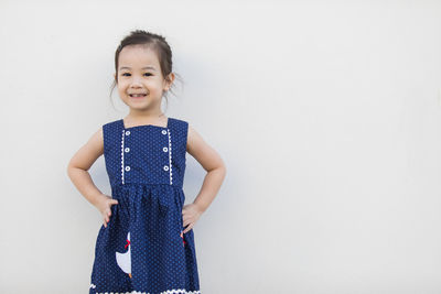 Portrait of smiling girl standing against wall