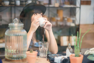 Women drinking coffee looking away while sitting at restaurant