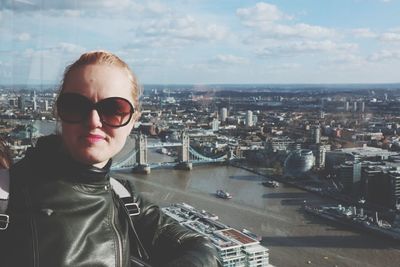 Portrait of woman wearing sunglasses standing against cityscape