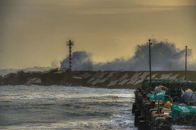 Lighthouse by sea against sky during sunset