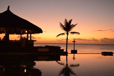 Silhouette swimming pool by sea against sky during sunset