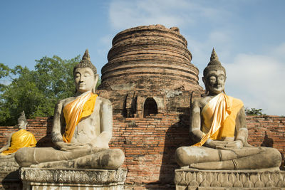 Buddha statues outside temple against blue sky