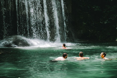 People swimming in waterfall