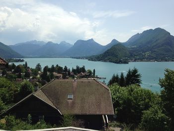 Houses by lake and mountains against sky