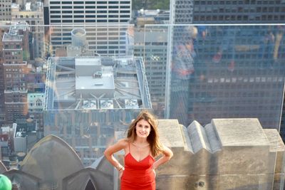 High angle portrait of woman against glass railing in city