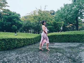 Full length of woman standing against trees in park