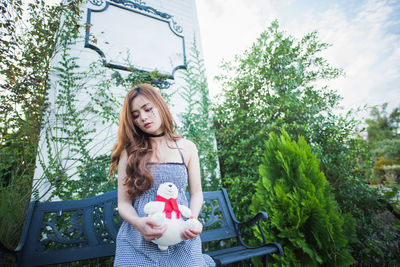 Woman holding teddy while standing at park