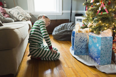 Elementary age boy looks sideways at christmas presents under the tree