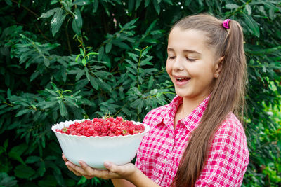 Smiling girl holding fruit in bowl