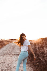 Portrait of smiling woman standing on road against clear sky