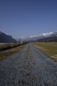 Empty road along landscape against clear sky