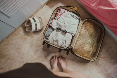 Low section of woman standing by luggage at home