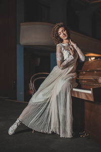 Young woman in dress sitting on piano