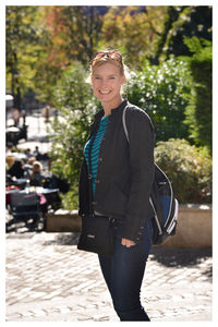 Portrait of smiling young woman standing against trees